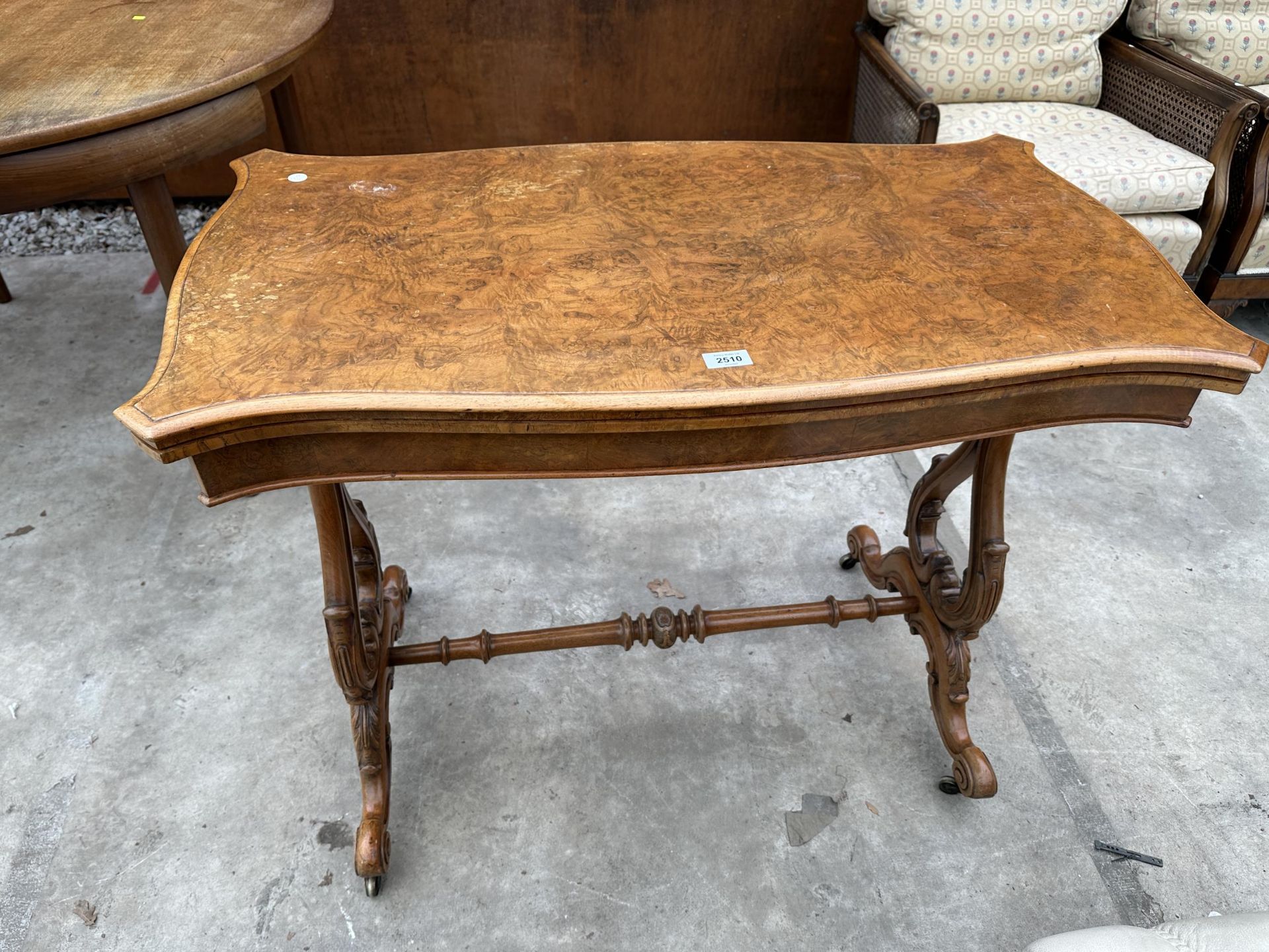 A VICTORIAN WALNUT FOLD OVER GAMES TABLE WITH LYRE SUPPORTS AND TURNED STRETCHER ON BRASS CASTERS