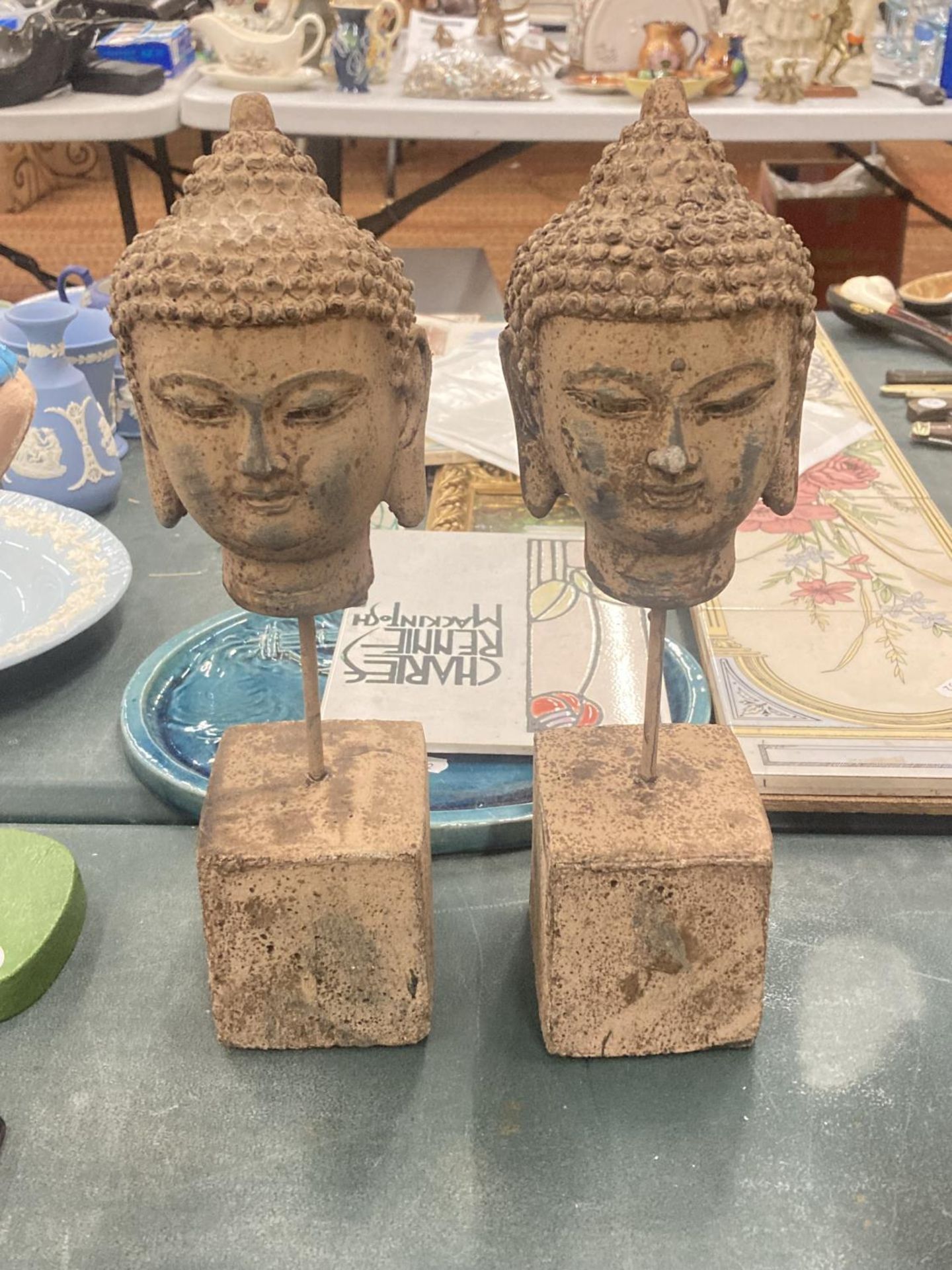 A PAIR OF STONE BUDDAHS HEADS ON PLINTHS, HEIGHT 30CM