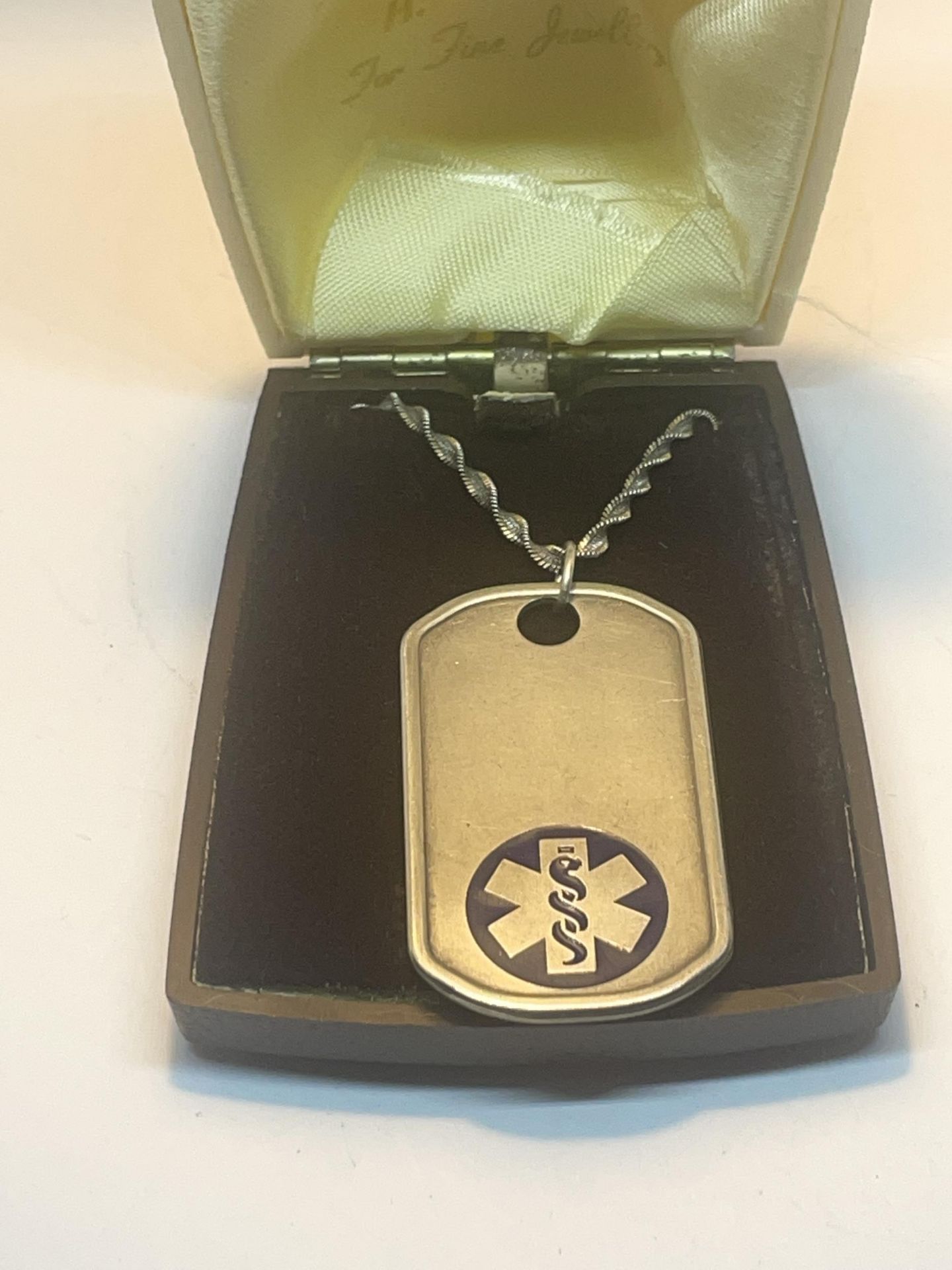 A MEDICAL PENDANT ON A MARKED SILVER CHAIN