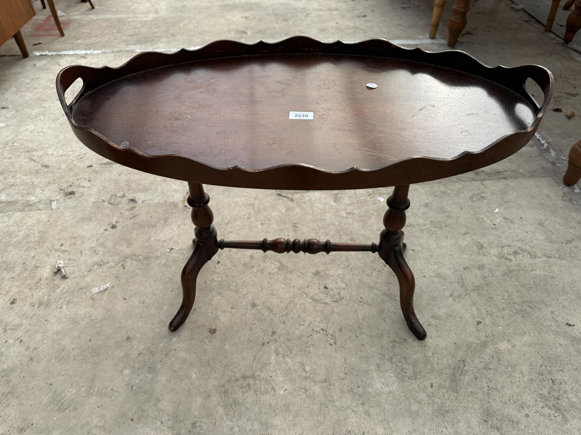AN OVAL OCCASIONAL TABLE WITH CARRYING HANDLE ON A PEDESTAL FRAME