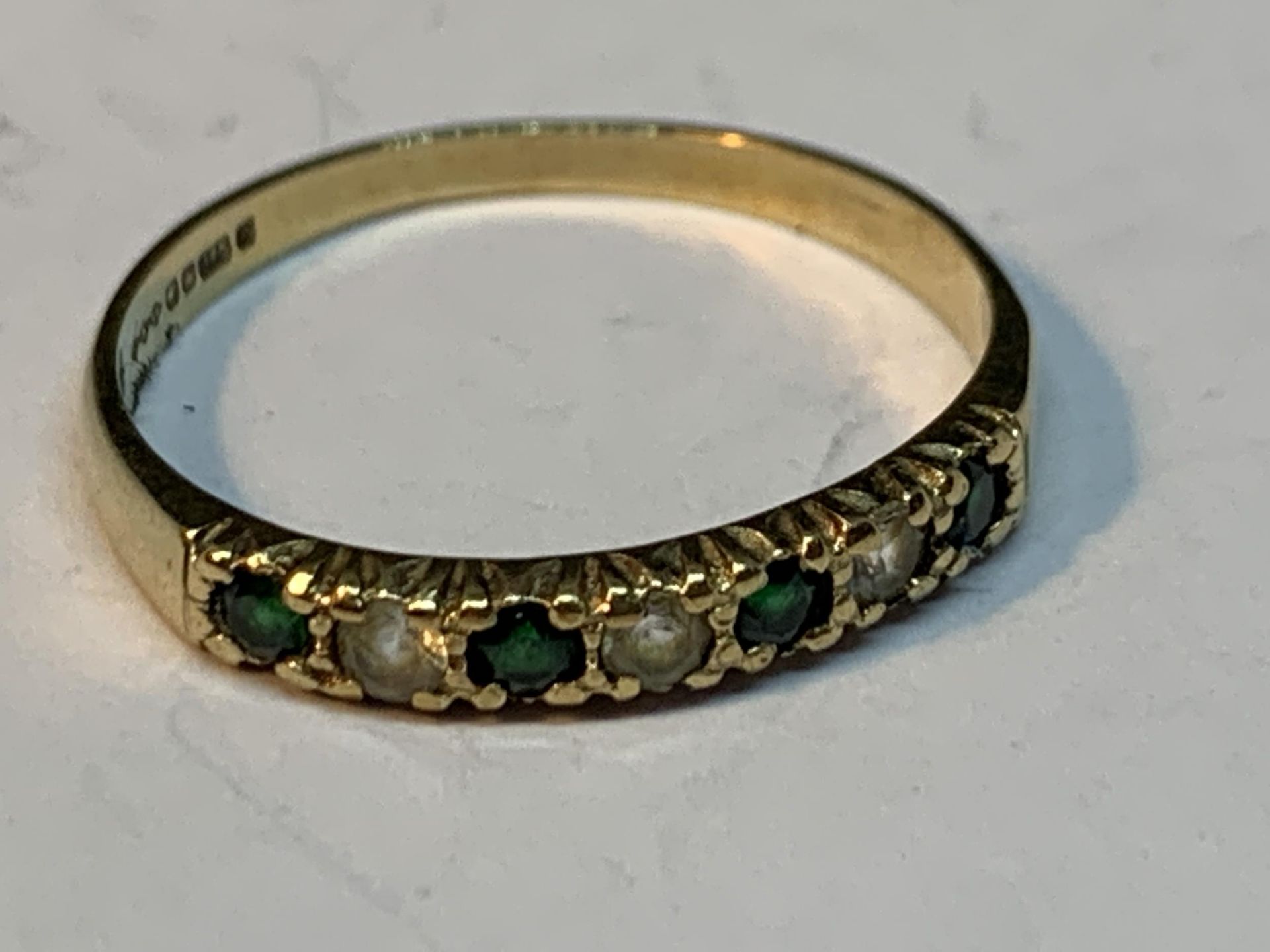 A 9 CARAT GOLD RING WITH FOUR EMERALDS AND THREE CUBIC ZIRCONIAS IN A LINE SIZE Q/R