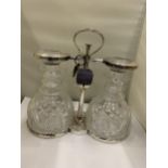 A WHITE METAL TANTALUS WITH TWO CUT GLASS DECANTERS WITH PADLOCK AND KEY