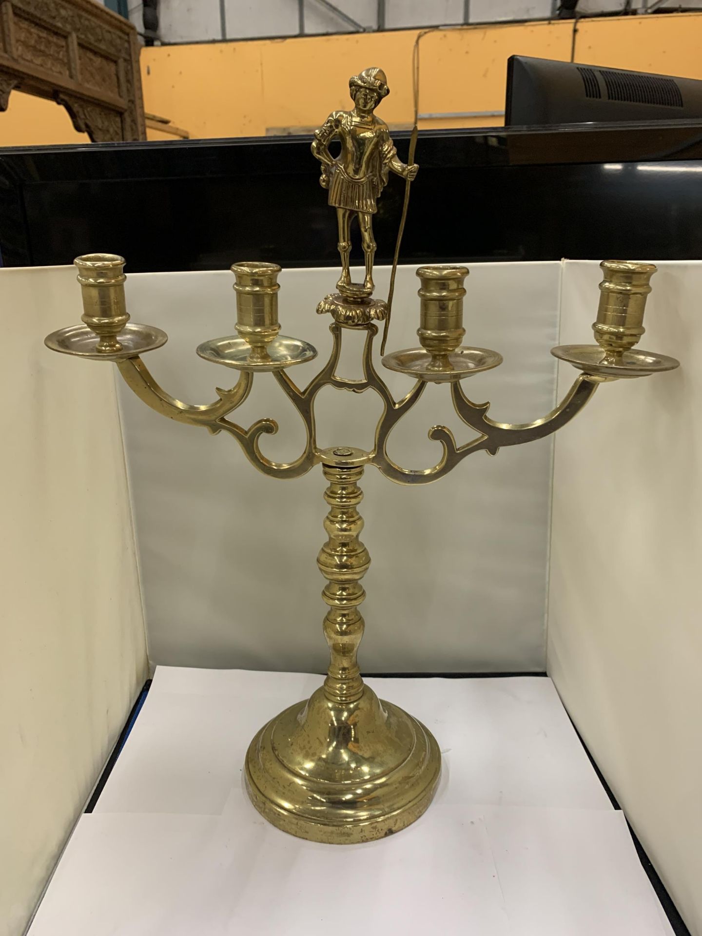 A HEAVY BRASS CANDELABRA WITH A FIGURE HOLDING A STAFF