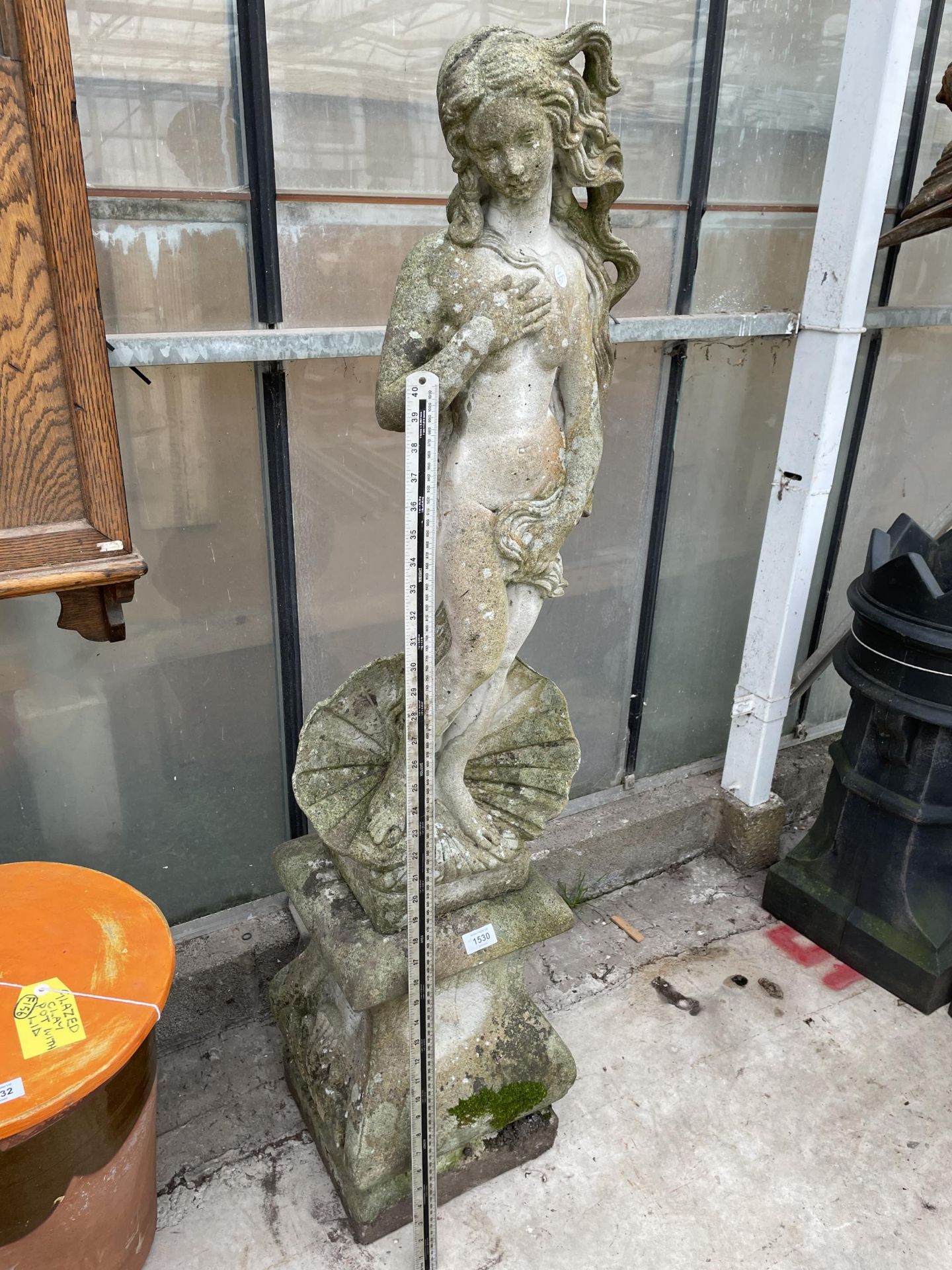 A TALL RECONSTITUTED STONE GARDEN FIGURE OF A FEMAL ON A PEDESTAL BASE (H:127CM)