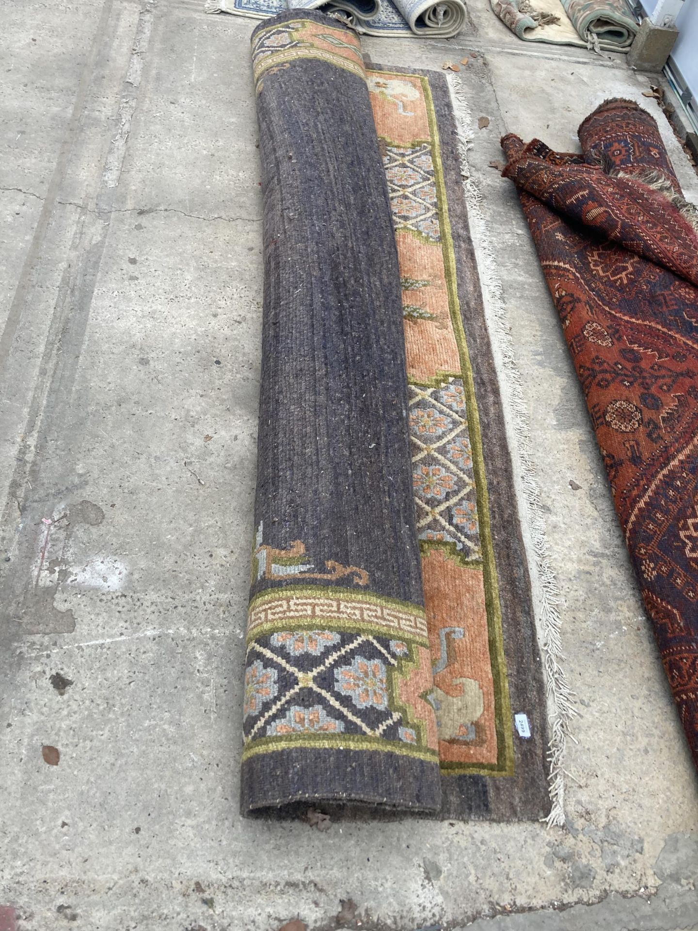 A LARGE MULTICOLOURED PATTERNED FRINGED RUG