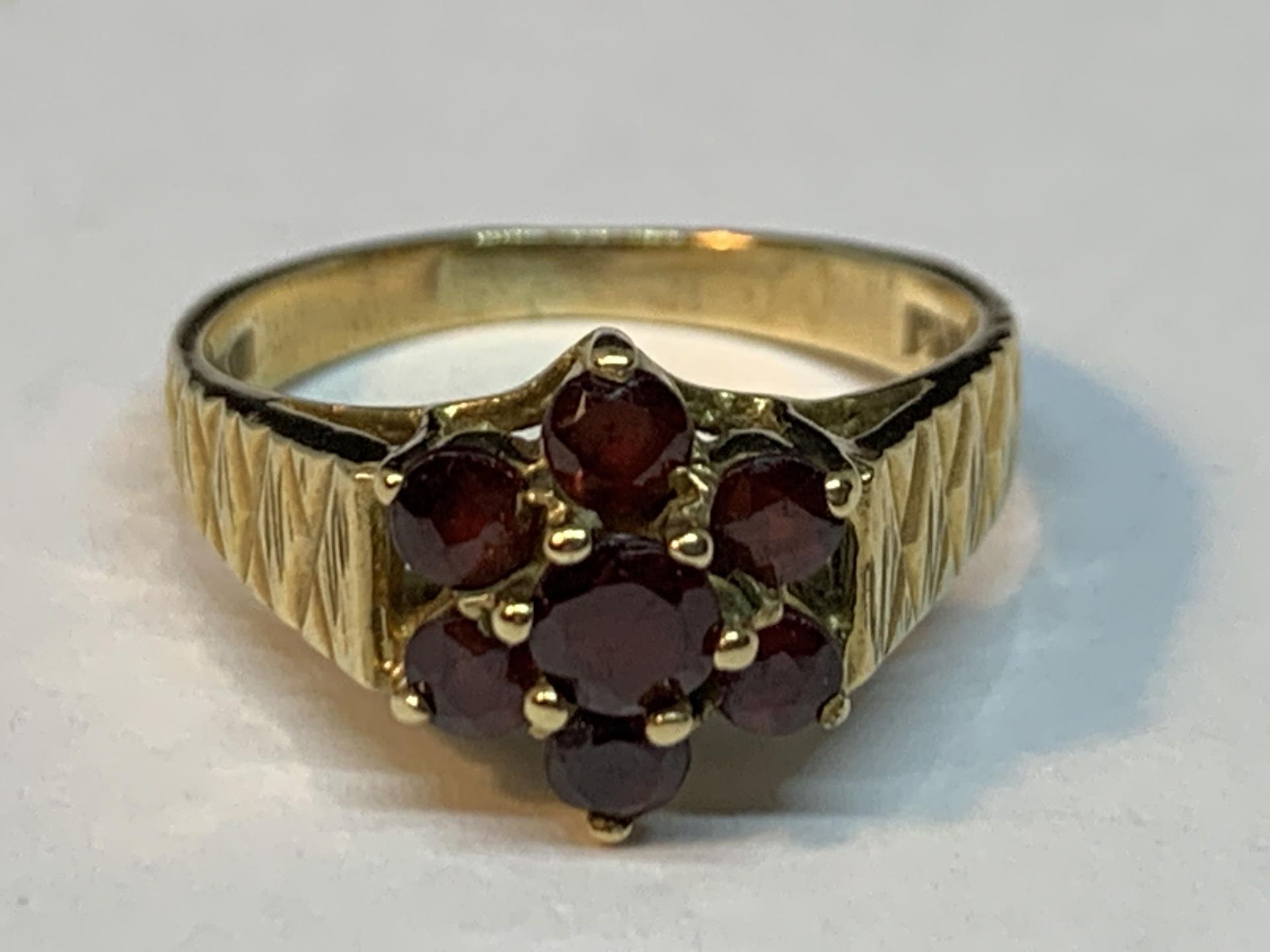 A 9 CARAT GOLD RING WITH GARNETS IN A CLUSTER DESIGN SIZE M