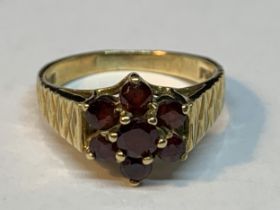 A 9 CARAT GOLD RING WITH GARNETS IN A CLUSTER DESIGN SIZE M