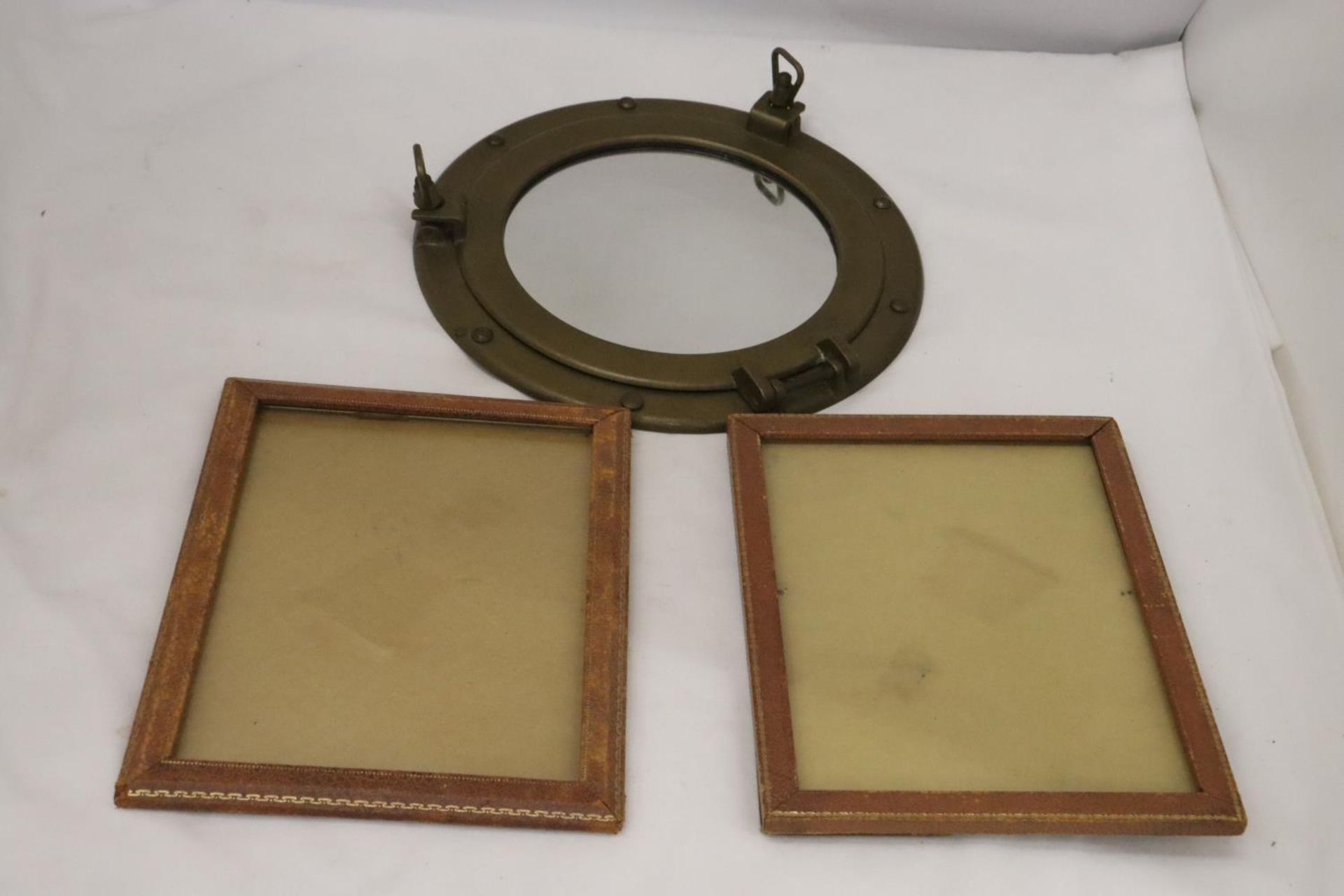 A BRASS PORTHOLE MIRROR WITH TWO WOODEN FRAMES