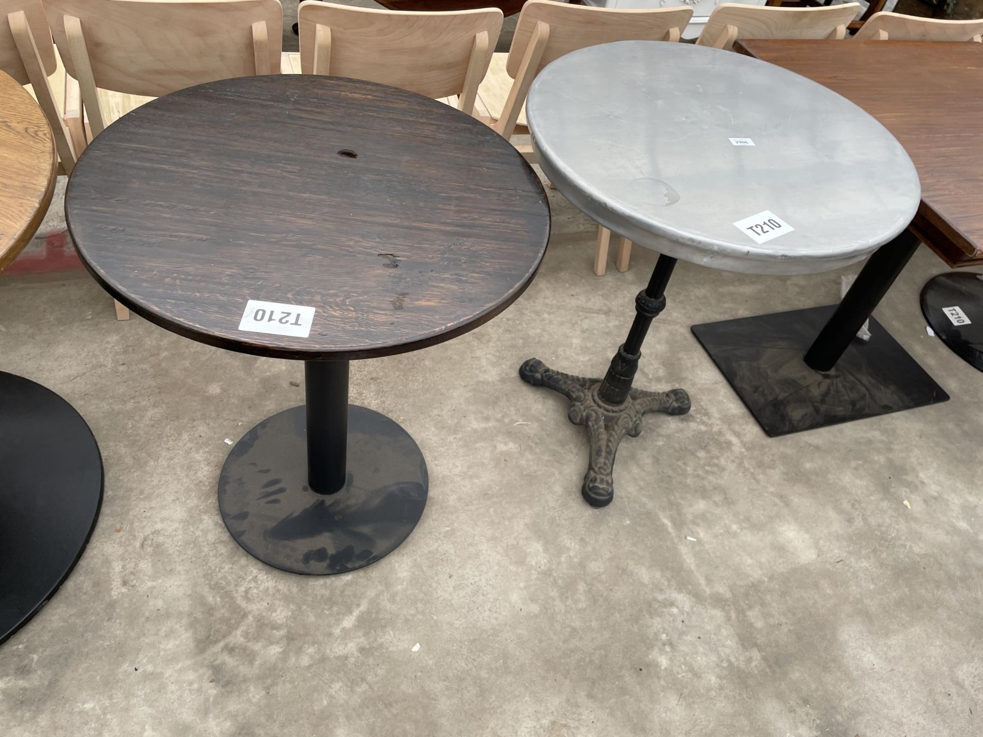 TWO PUB TABLES ONE ON A CAST IRON BASE 25" DIAMETER AND ONE ON A METALWARE BASE 26" DIAMETER