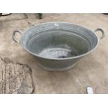 A SMALL OVAL GALVANISED TIN BATH