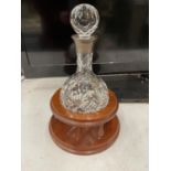 A CUT CLASS ROUND BOTTOM DECANTER WITH HALLMARKED BIRMINGHAM SILVER COLLAR ON A WOODEN BASE (BASEA/