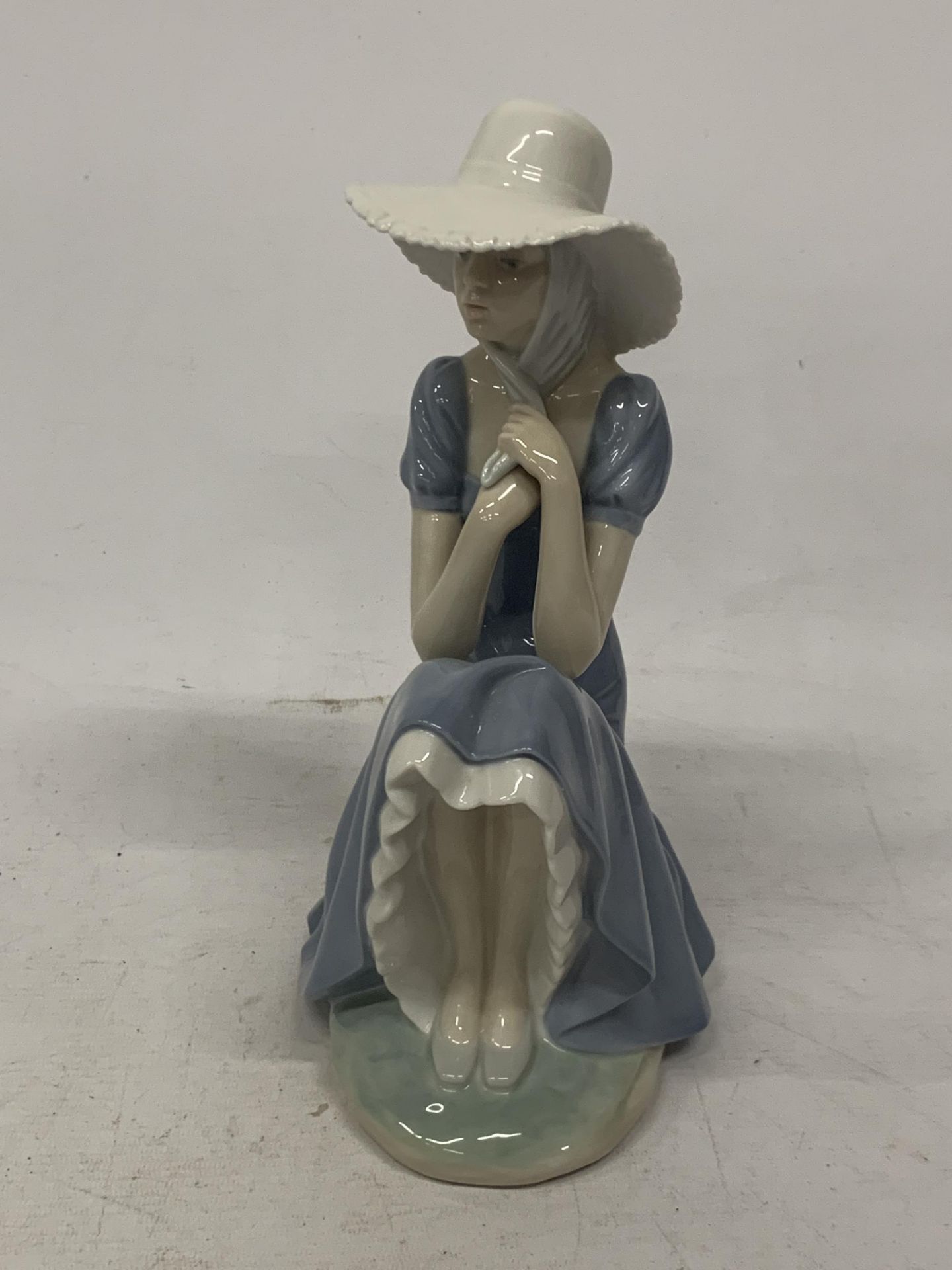 A NAO FIGURE OF A GIRL HOLDING HER BONNET STRAPS