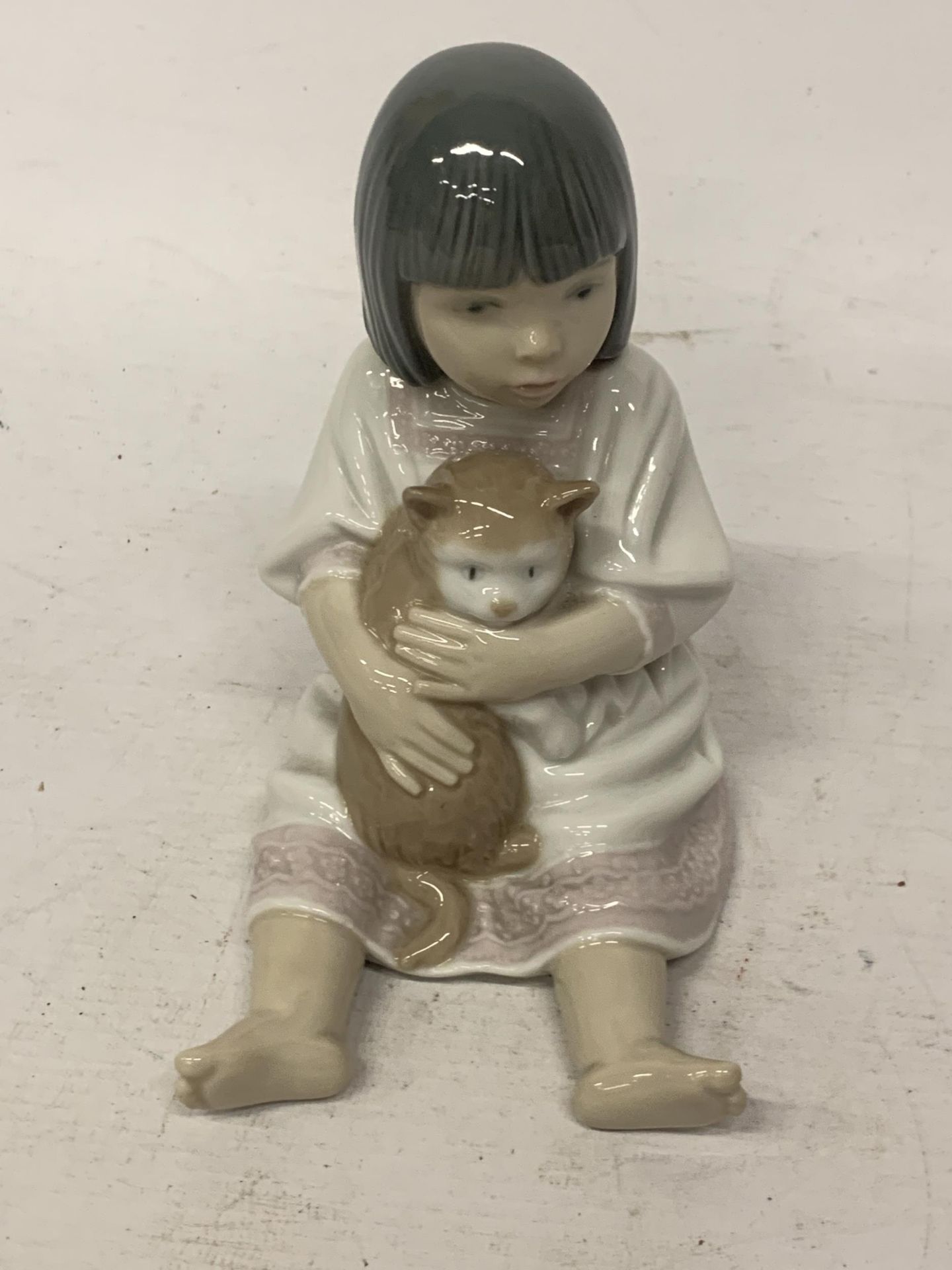 A NAO FIGURE OF OF A GIRL CUDDLING HER PUSSY