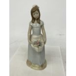 A NADAL FIGURE OF A GIRL CARRYING FLOWERS IN HER APRON