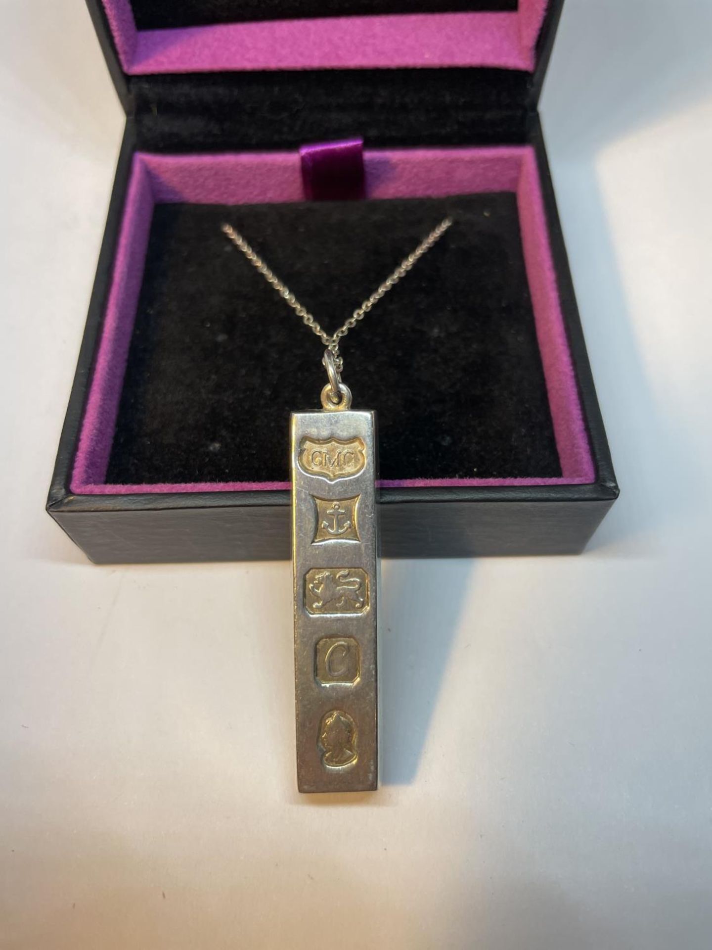 A SILVER INGOT ON A CHAIN IN A PRESENTATION BOX