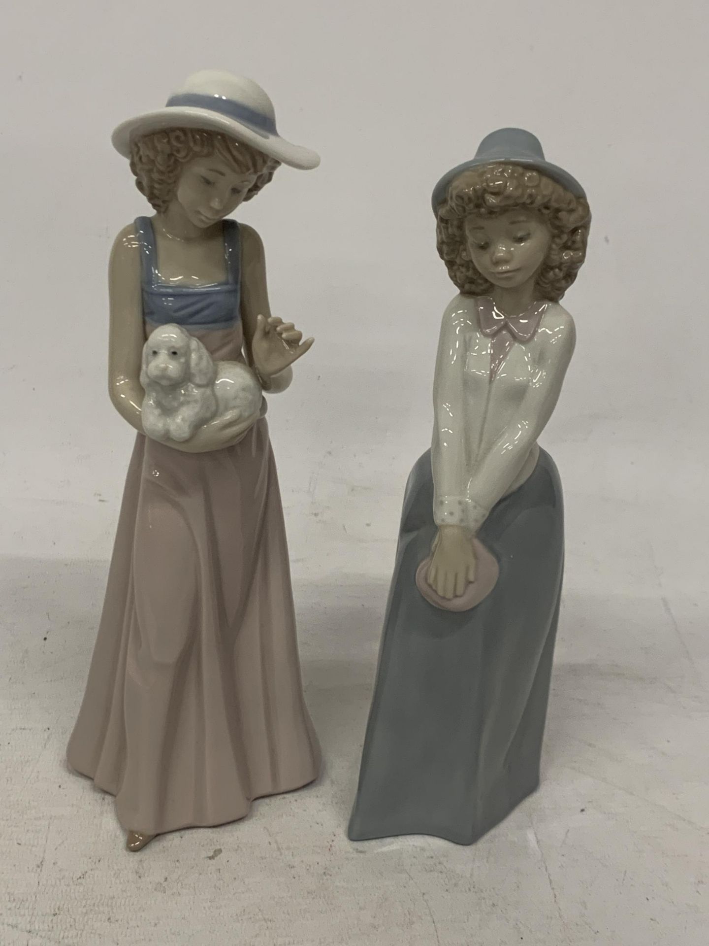 TWO NAO FIGURES OF GIRLS TO INCLUDE ONE HOLDING A PUPPY