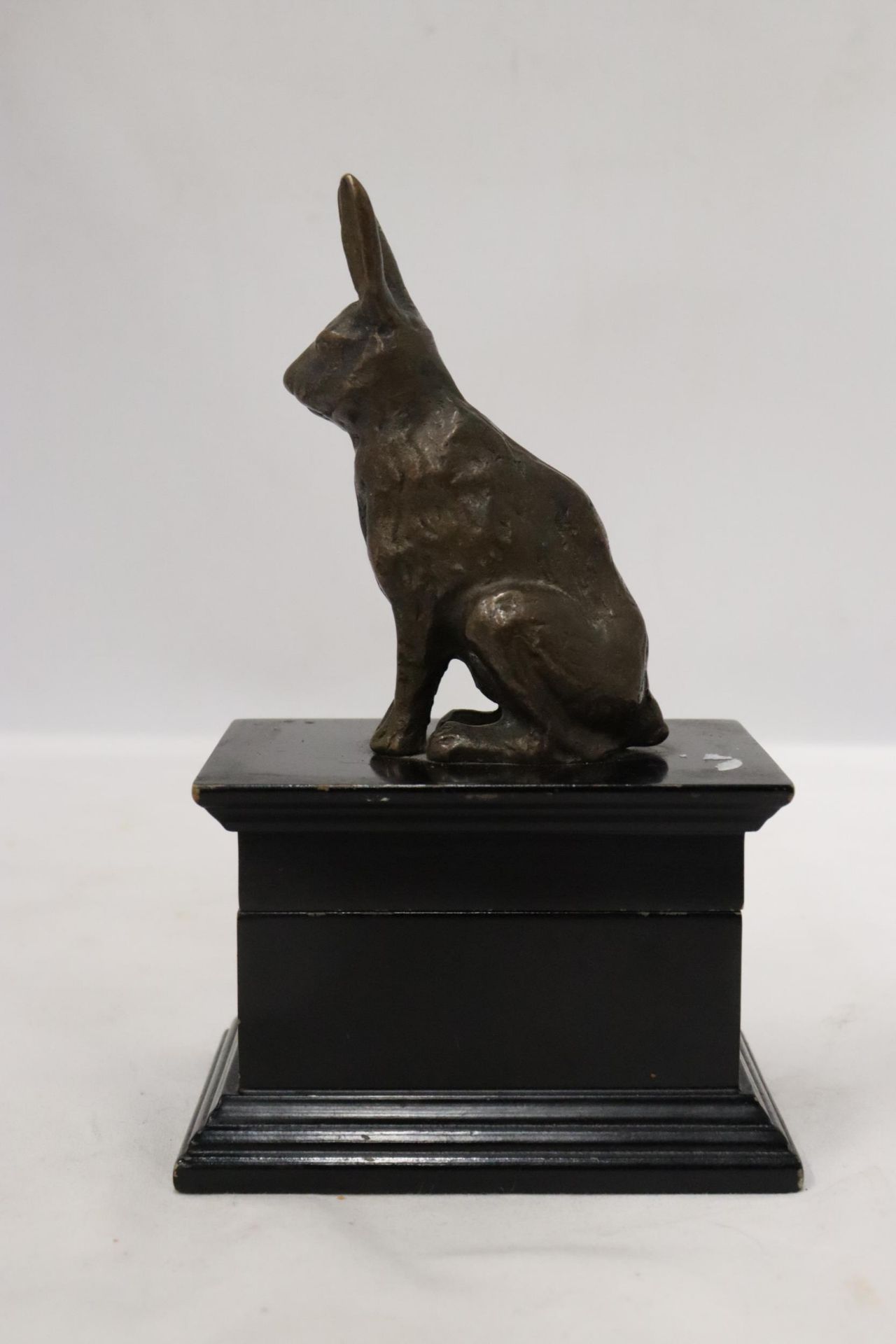 A FIGURE OF A HARE SITTING ON A WOODEN TRINKET BOX