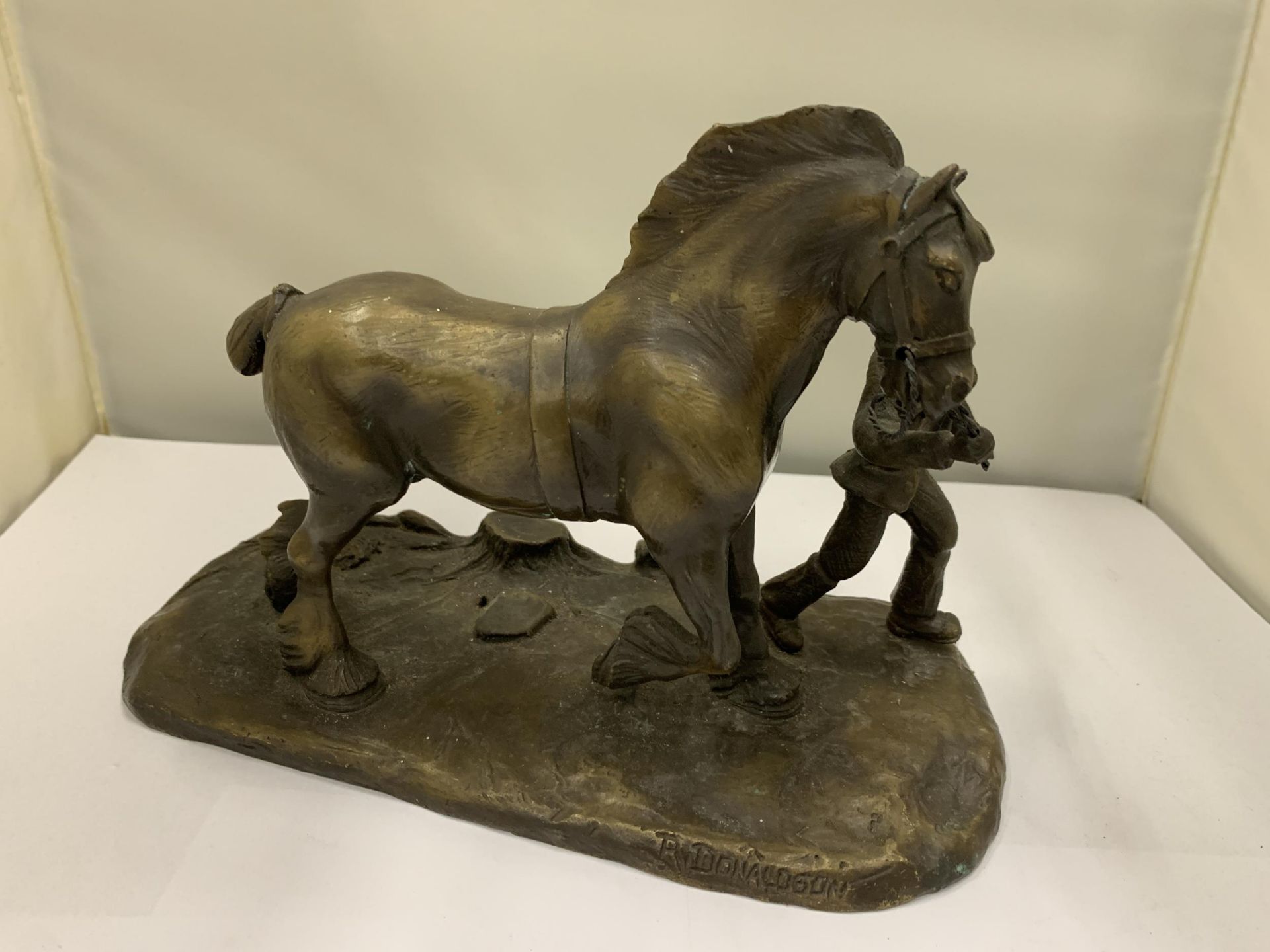 A BRONZE FIGURE OF A MAN WITH A HEAVY HORSE SIGNED R DONALDSON