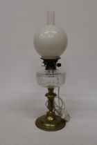 A 19TH CENTURY OIL LAMP CONVERTED TO ELECTRIC WITH A BRASS BASE, CLEAR CUT GLASS RESERVOIR, MILK