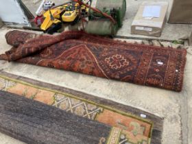 A LARGE VINTAGE RED PATTERNED FRINGED RUG