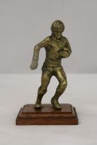 A VINTAGE BRASS RUGBY PLAYER ON A WOODEN PLINTH