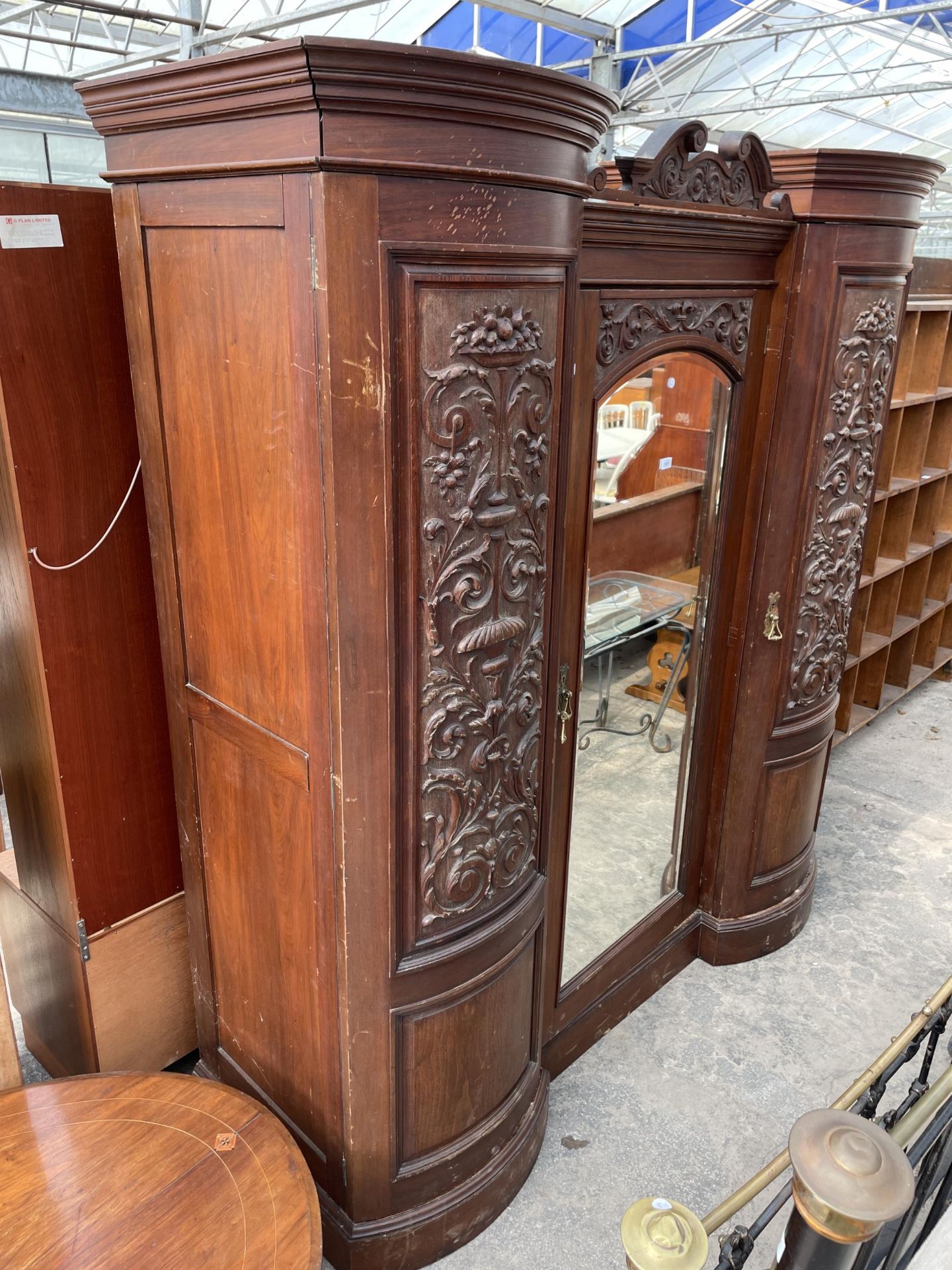 A VICTORIAN MAHOGANY DOUBLE BOW FRONTED MIRROR DOOR WARDROBE WITH FOLIATE CARVED PANELS AND THREE - Image 2 of 10