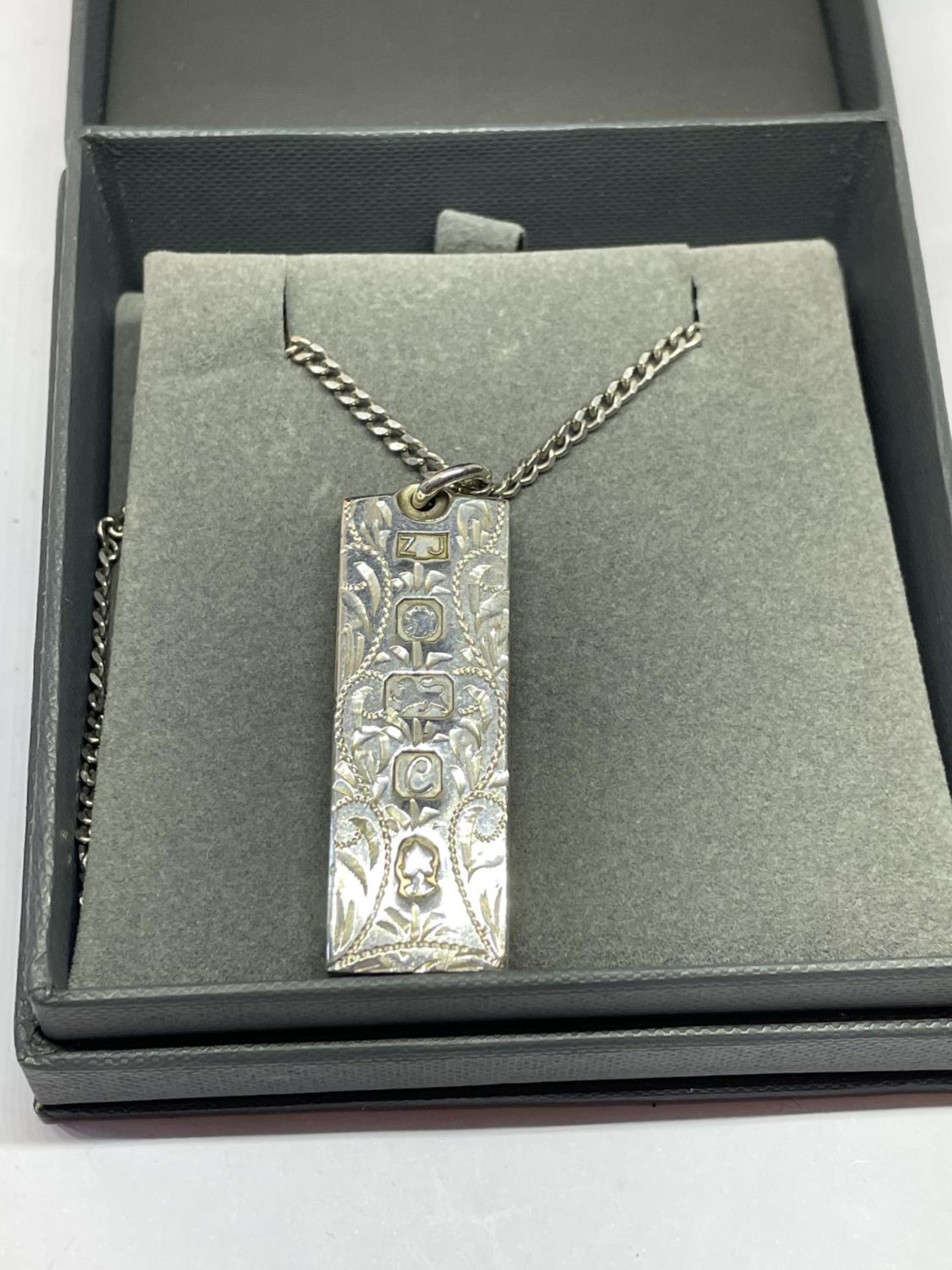 AN ORNATE SILVER INGOT AND CHAIN IN A PRESENTATION BOX