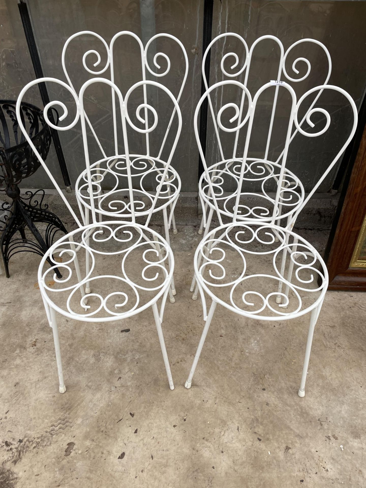 A SET OF FOUR ORNATE AND DECORATIVE WROUGHT IRON BISTRO CHAIRS