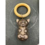 AN EARLY 20TH CENTURY TEETHING RING WITH TEDDY BEAR CHARM