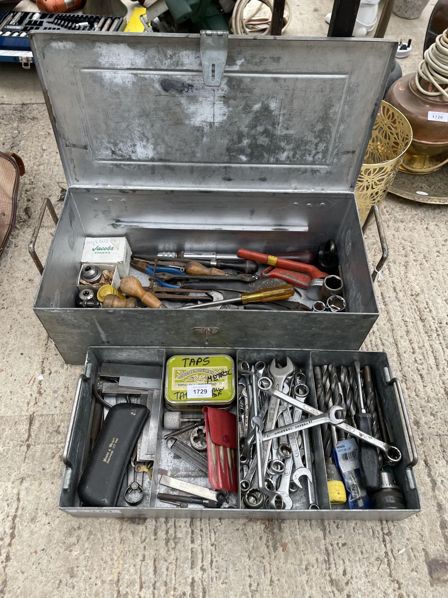 A METAL TOOL BOX WITH AN ASSORTMENT OF TOOLS TO INCLUDE SPANNERS, DRILL BITS AND PLIERS ETC