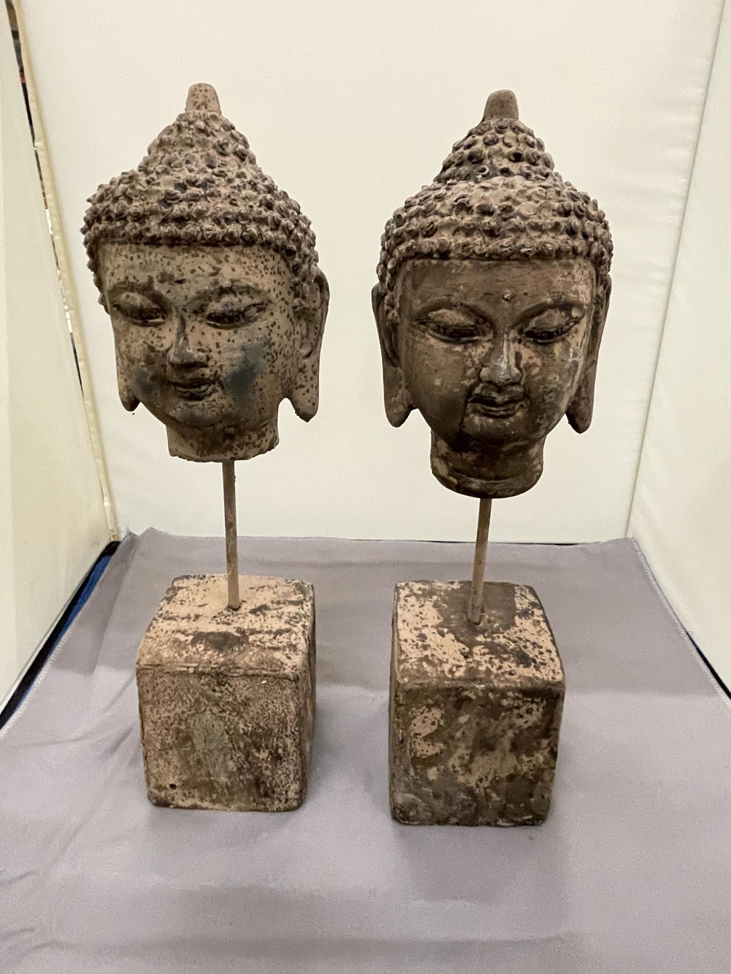 TWO STONE BUDDAHS HEADS ON PLINTHS, HEIGHT 30CM