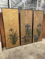 THREE PAINTED FLORAL PANELS IN EBONISED FRAMES