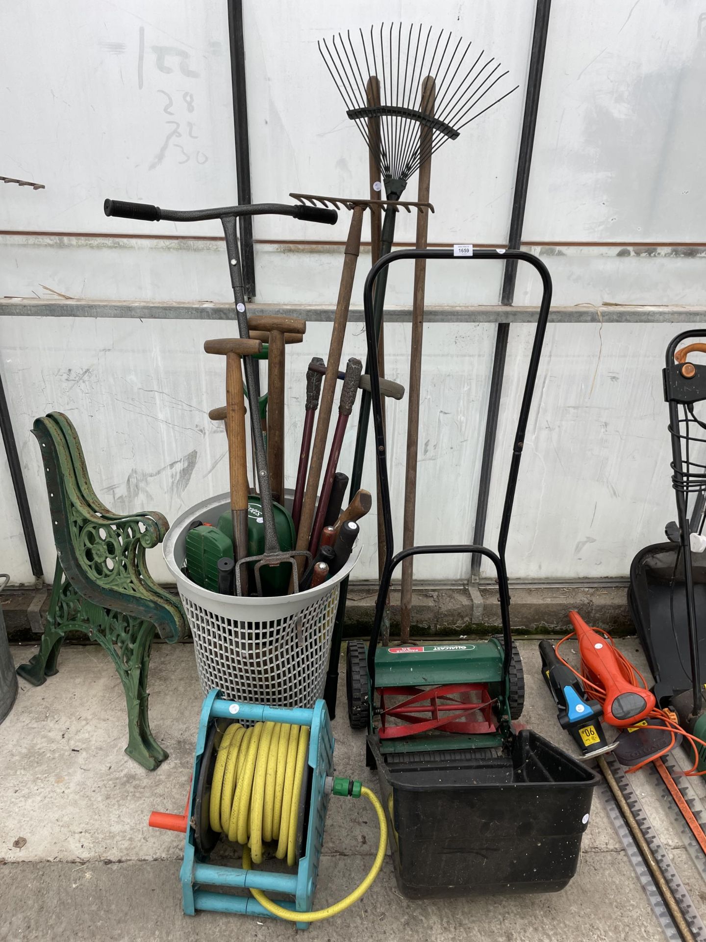 AN ASSORTMENT OF GARDEN TOOLS TO INCLUDE A LAWN MOWER, RAKES AND FORKS ETC