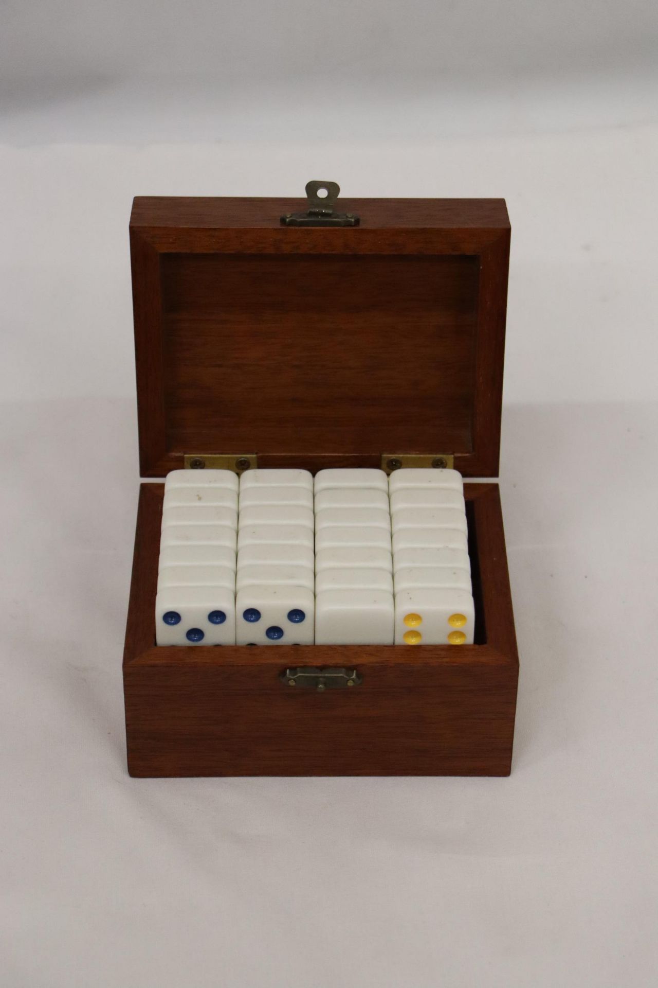 A WOODEN BOX CONTAINING A SET OF BONE DOMINOES