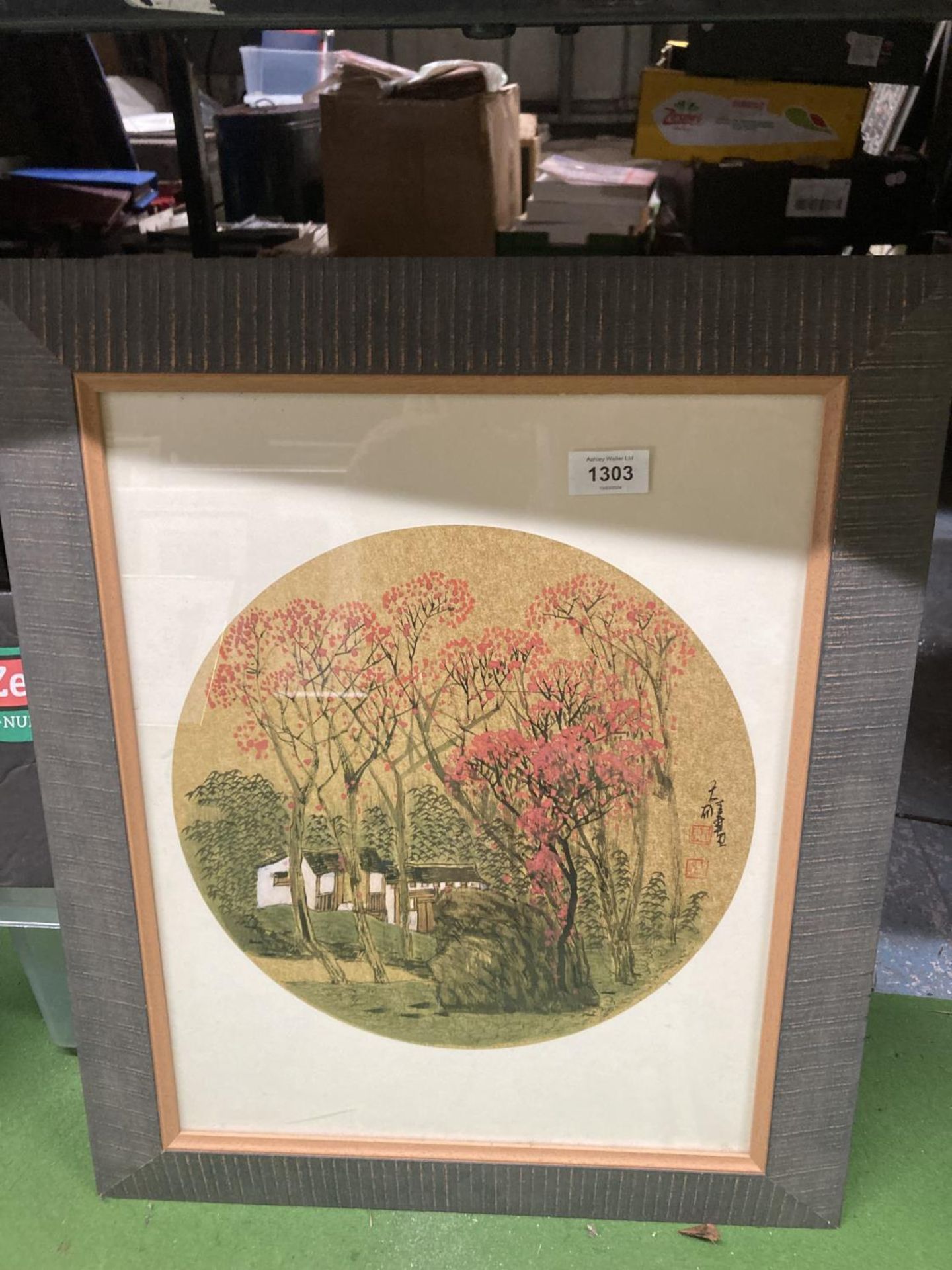 A FRAMED ORIENTAL METALLIC PRINT OF HOUSES AND PRUNUS