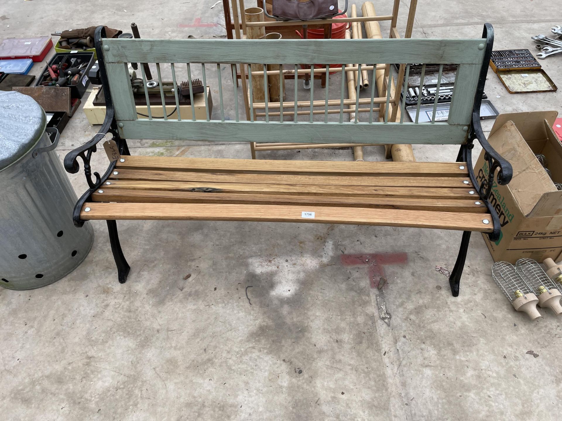 A WOODEN SLATTED GARDEN BENCH WITH DECORATIVE CAST BENCH ENDS