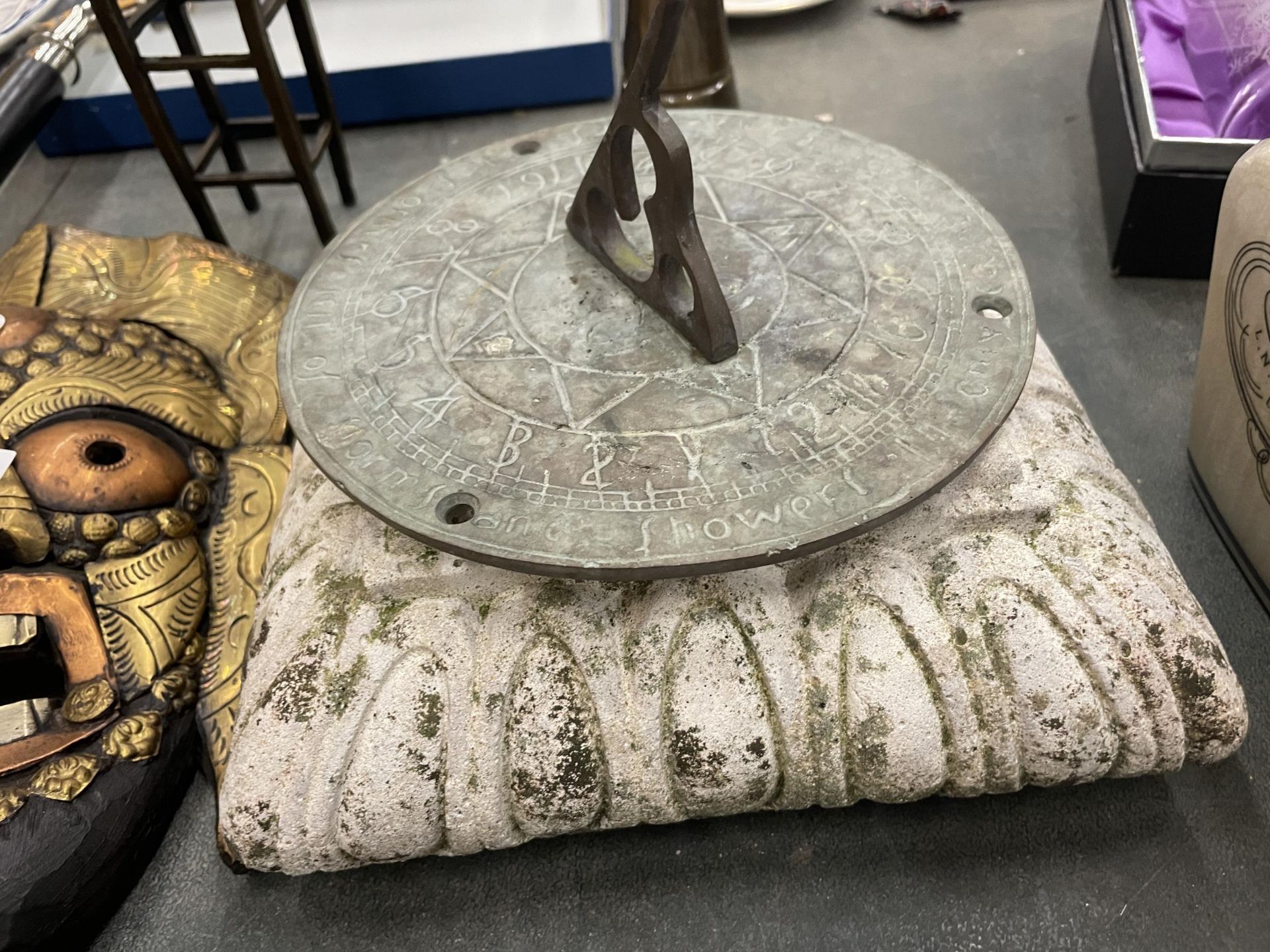 A BRASS SUN DIAL ON A CONCRETE BASE