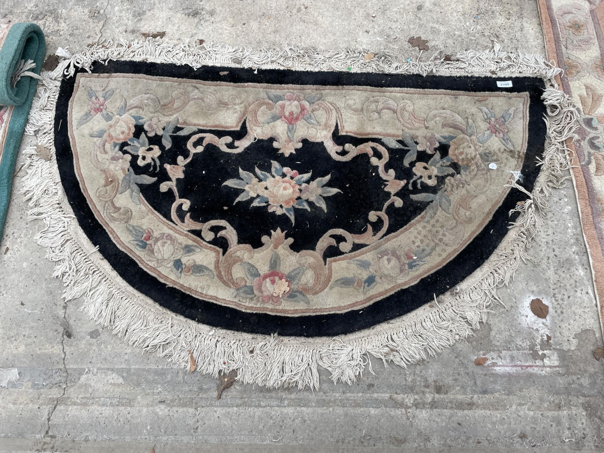 A BLACK PATTERNED HALF MOON FRINGED RUG