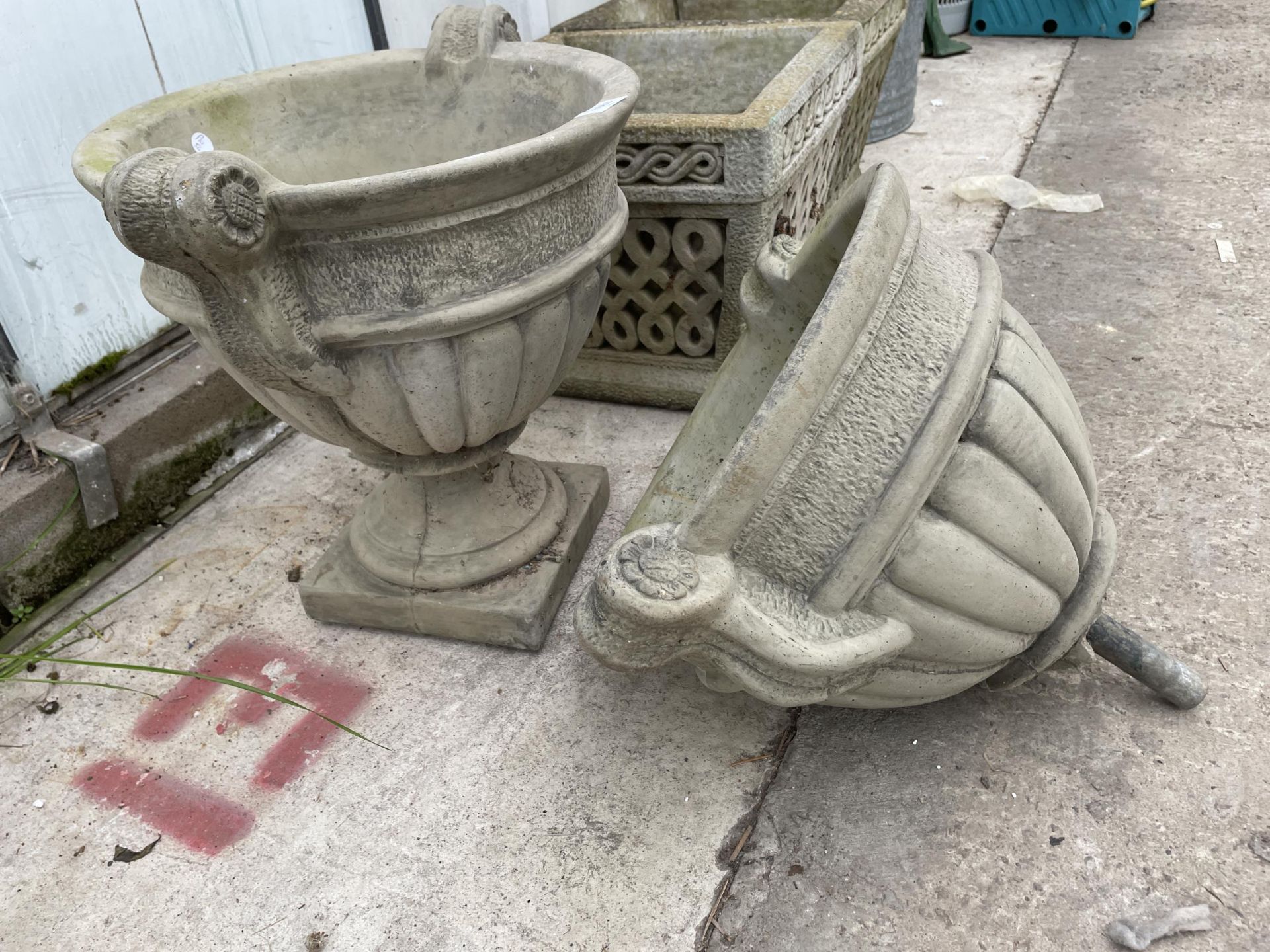 A CONCRETE GARDEN URN PLANTER WITH BASE AND A FURTHER URN PLANTER LACKING THE BASE