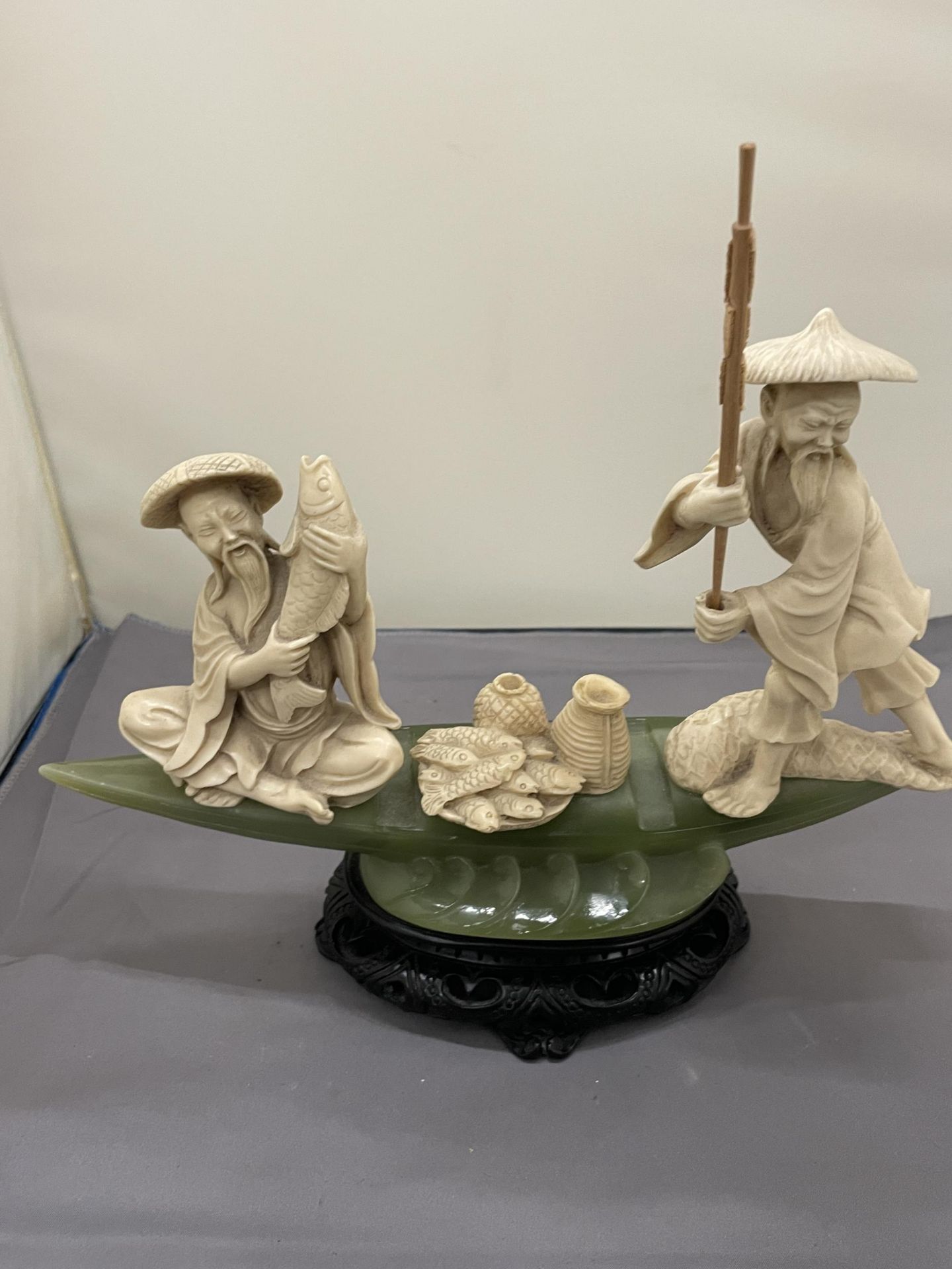 AN ORIENTAL CARVING OF FISHERMEN ON A POSSIBLY JADE BOAT, HEIGHT 20CM, WIDTH 27CM