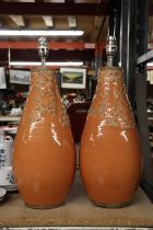 A LARGE PAIR OF STUDIO POTTERY LAMP BASES IN ORANGE WITH EMBOSSED LEAF DESIGN, HEIGHT APPROX 40CM