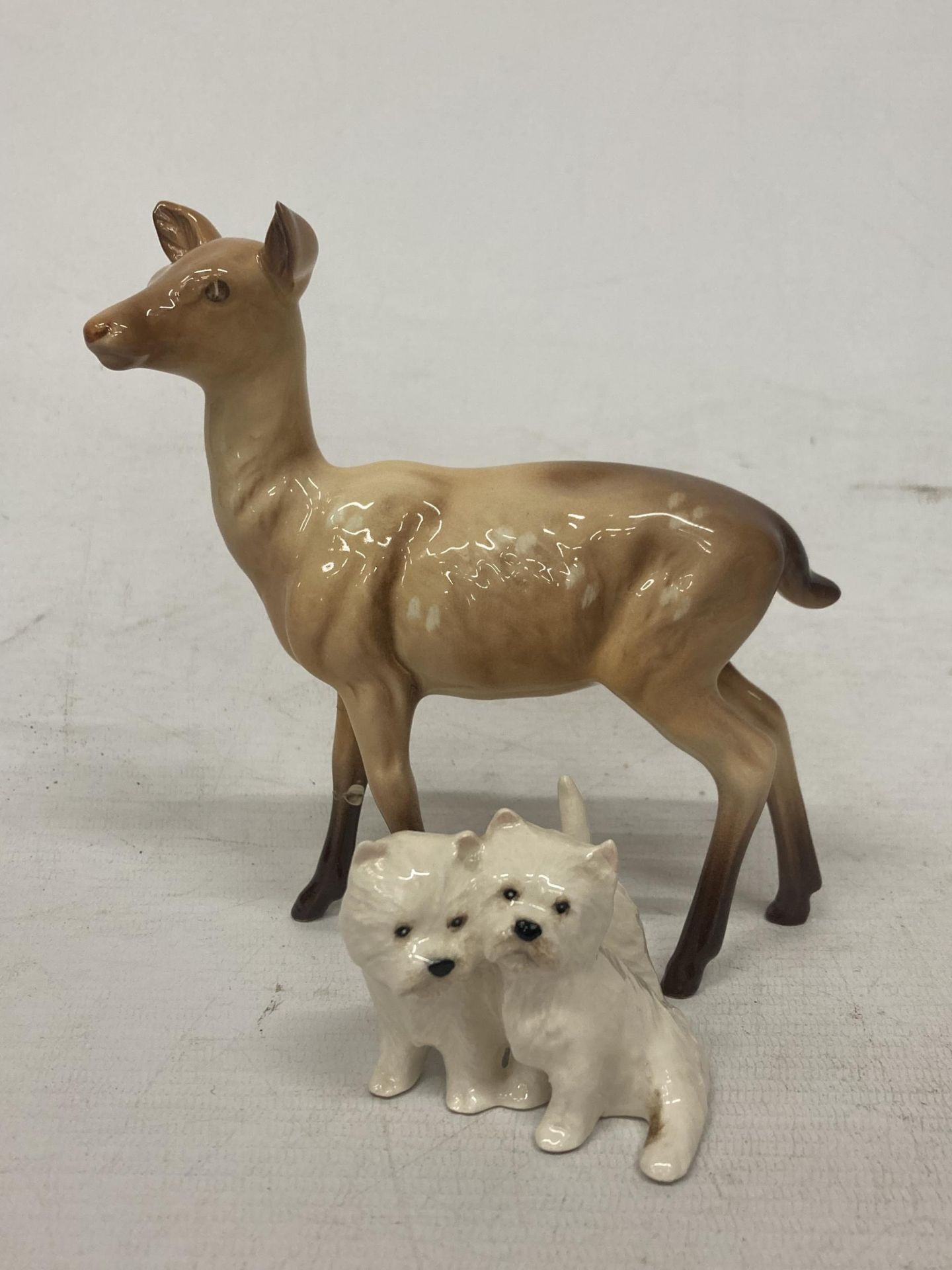 A PAIR OF BESWICK SITTING WEST HIGHLAND TERRIERS TOGETHER WITH A BESWICK DEER FIGURE (A/F)