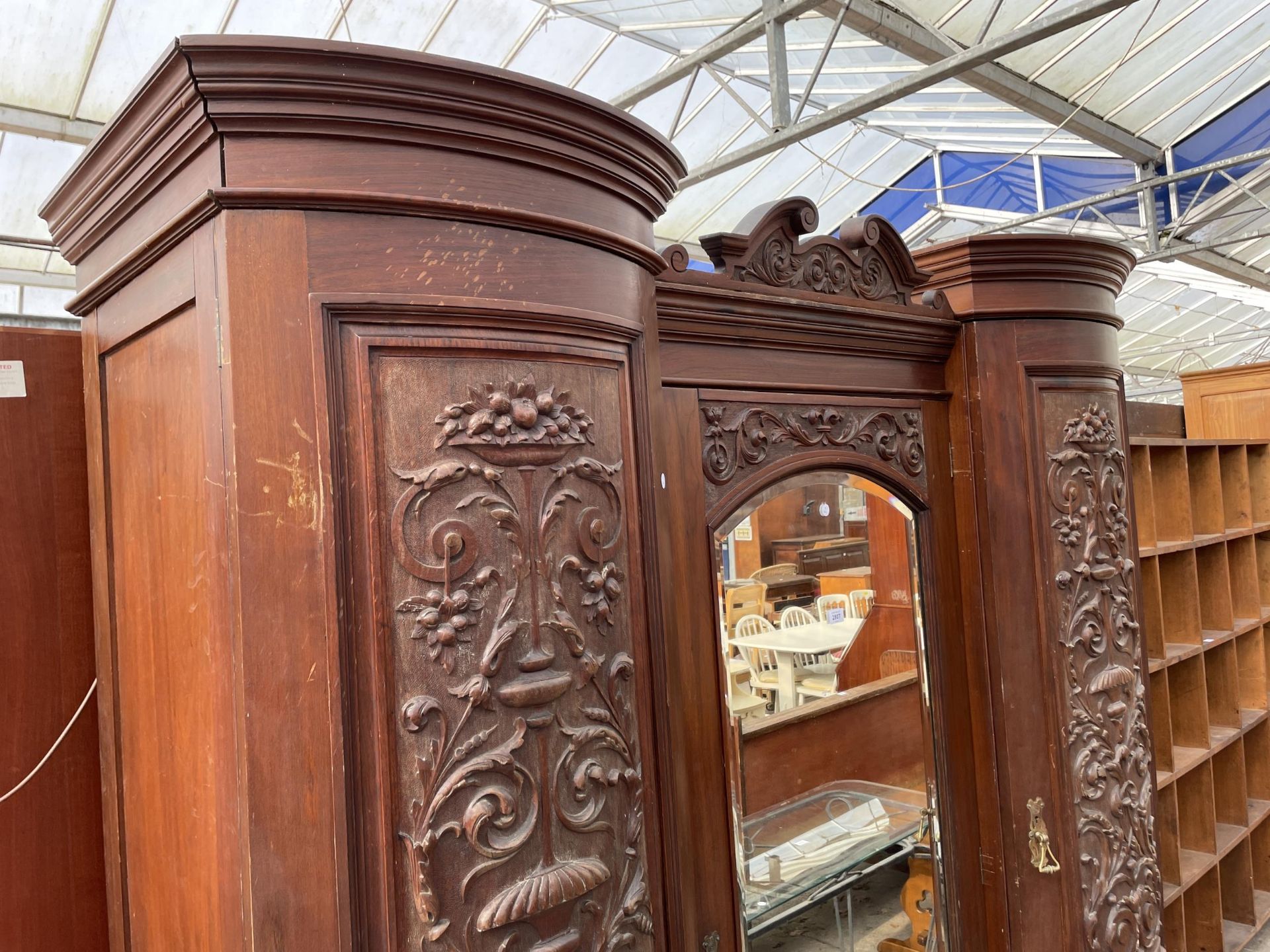 A VICTORIAN MAHOGANY DOUBLE BOW FRONTED MIRROR DOOR WARDROBE WITH FOLIATE CARVED PANELS AND THREE - Image 3 of 10