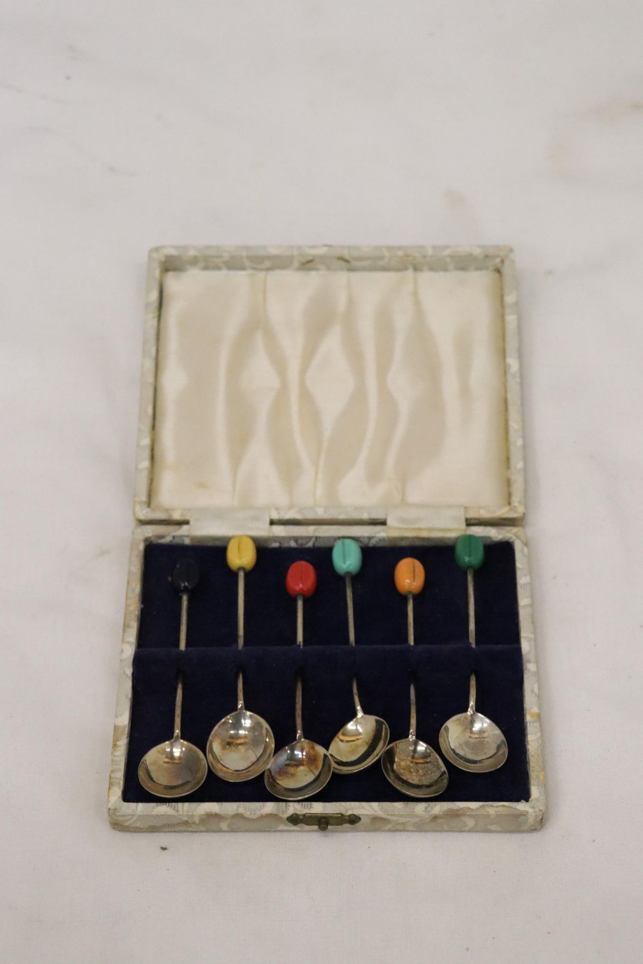 A SET OF SIX HALLMARKED SHEFFIELD SILVER COFFEE BEAN SPOONS WITH VARIOUS COLOURED TOPS IN A