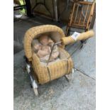 A SMALL VINTAGE WICKER PRAM WITH DOLL