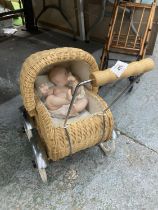 A SMALL VINTAGE WICKER PRAM WITH DOLL