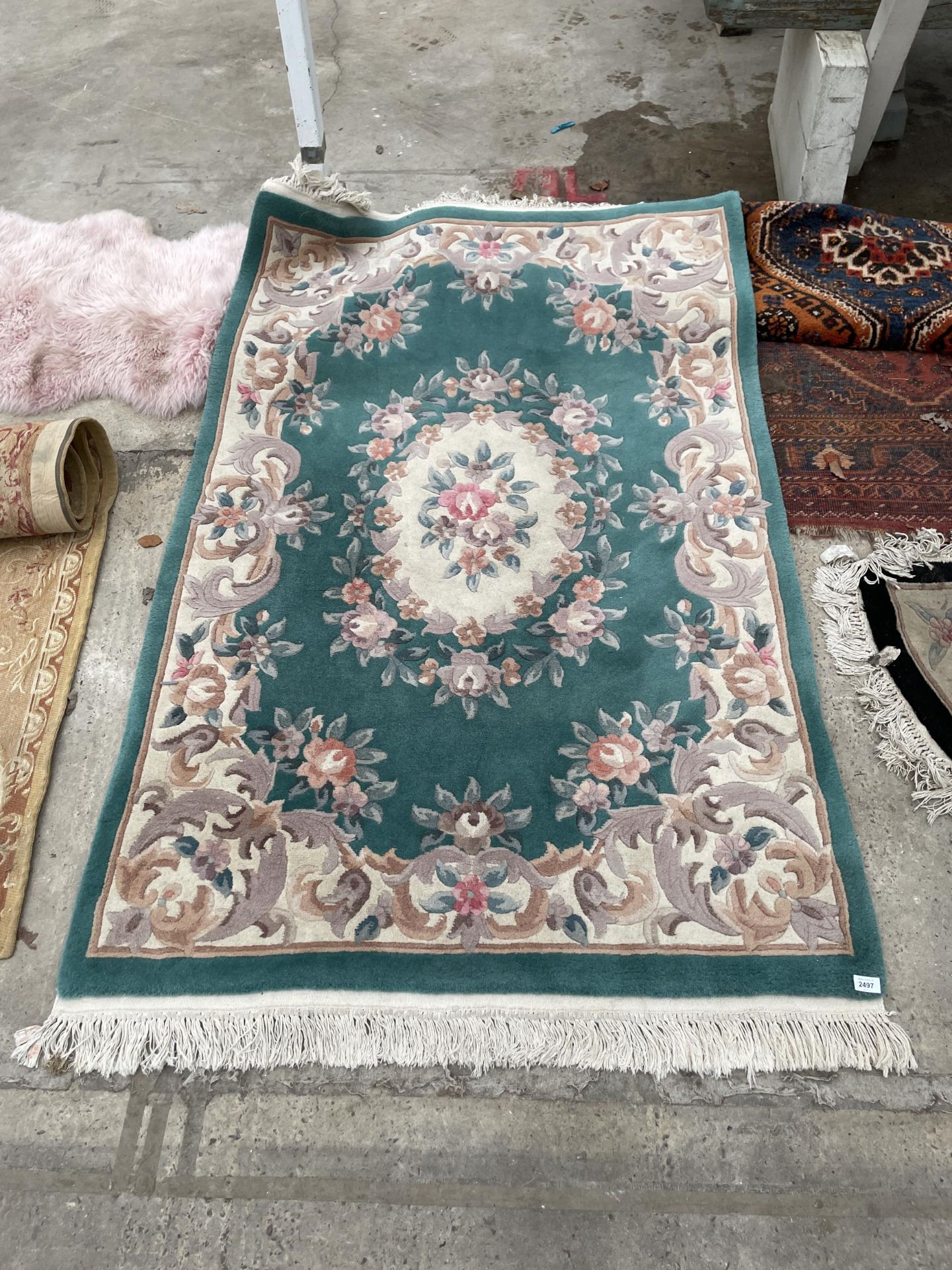 A GREEN PATTERNED FRINGED RUG