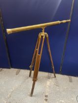 A BRASS TELESCOPE ON AN ADJUSTABLE TRIPOD STAND