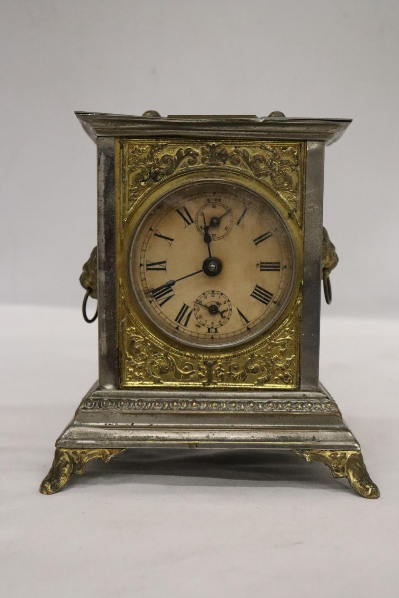 AN ORNATE VINTAGE ALARM CARRIAGE CLOCK WITH LION HANDLE DECORATION TO THE SIDES - POSSIBLY AN