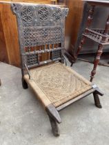 AN INDIAN TRIBAL LOW CHAIR WITH CARVED BACK AND WOVEN SEAT